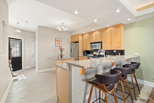 kitchen featuring stainless steel appliances, recessed lighting, light brown cabinetry, a kitchen island, and a peninsula