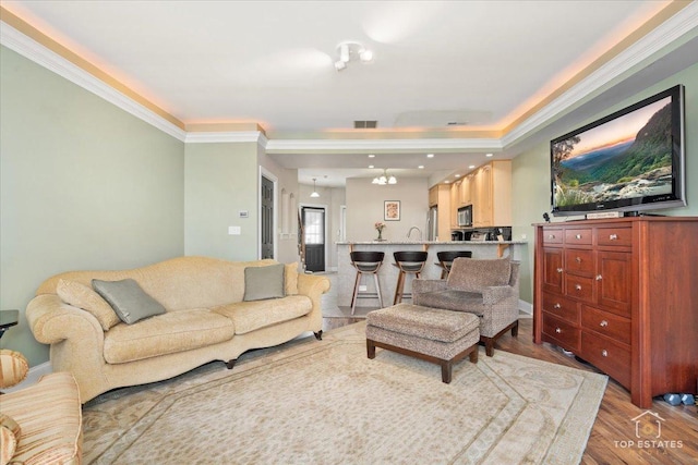 living area with baseboards, wood finished floors, visible vents, and crown molding