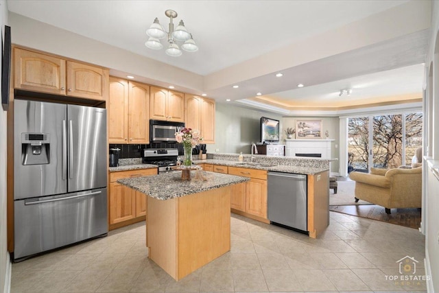 kitchen with a peninsula, light brown cabinets, stainless steel appliances, and open floor plan