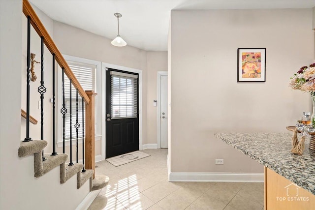 foyer entrance with stairs, baseboards, and light tile patterned floors