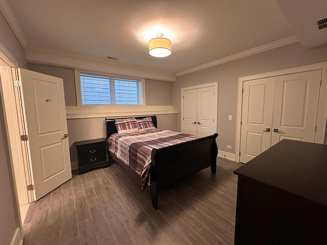 bedroom featuring multiple closets, crown molding, and dark wood-style flooring