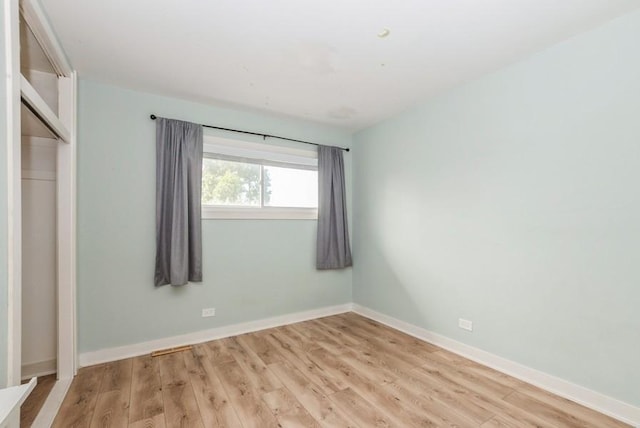 unfurnished bedroom featuring light wood-style floors, baseboards, and a closet