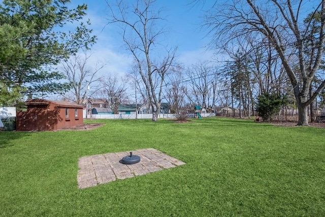 view of yard featuring a storage unit, an outdoor structure, and fence