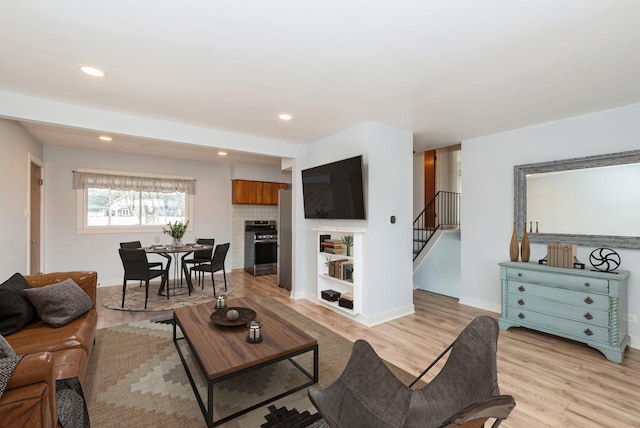 living area featuring stairway, radiator, light wood-style flooring, recessed lighting, and a fireplace