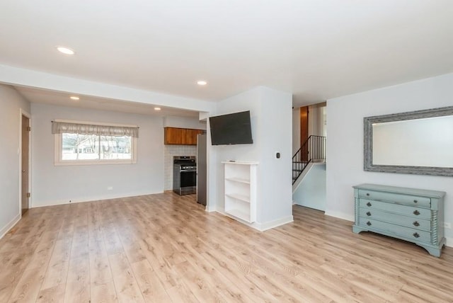 unfurnished living room featuring recessed lighting, light wood-style floors, a fireplace, and stairs