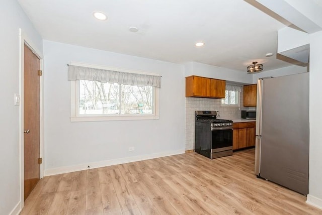 kitchen featuring light wood-style flooring, stainless steel appliances, decorative backsplash, light countertops, and brown cabinets