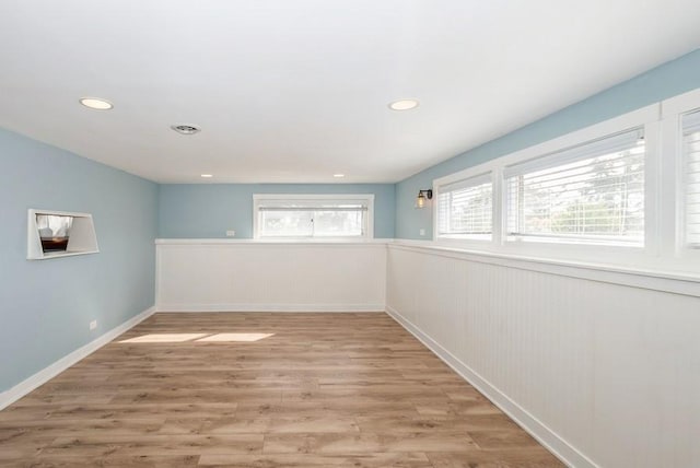 empty room featuring recessed lighting, light wood finished floors, and wainscoting