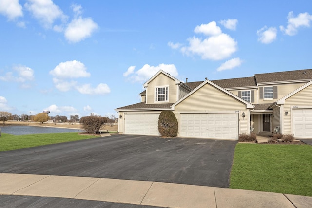 view of front of home featuring a garage, aphalt driveway, a front yard, and a water view