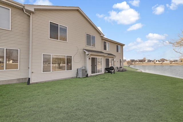 rear view of house with a water view, central AC unit, and a lawn