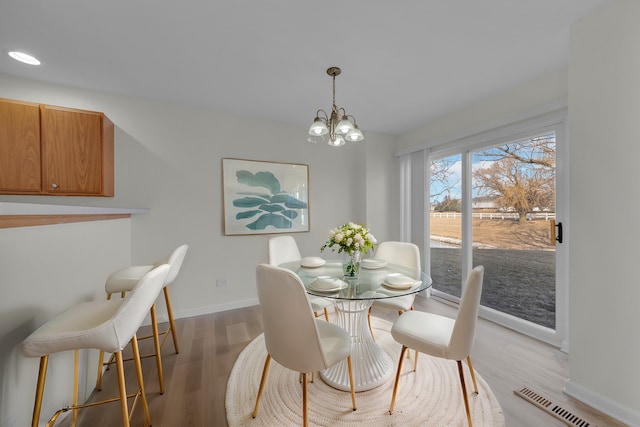 dining area featuring baseboards, wood finished floors, visible vents, and an inviting chandelier