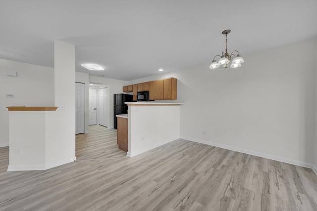 kitchen with baseboards, light wood finished floors, black appliances, and a peninsula