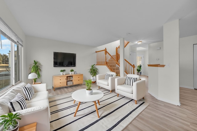 living area featuring stairs, baseboards, and wood finished floors