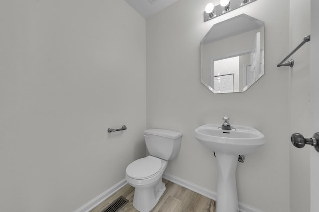 bathroom with a sink, wood finished floors, toilet, and baseboards