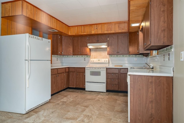 kitchen featuring brown cabinets, light countertops, a sink, white appliances, and under cabinet range hood