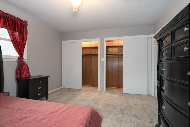 bedroom with light colored carpet and two closets