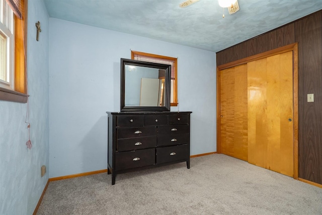 bedroom with a closet, light colored carpet, and baseboards