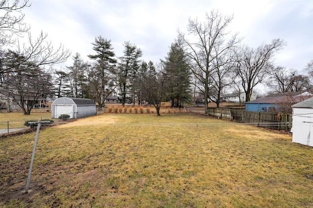 view of yard with a detached garage, fence, and an outdoor structure