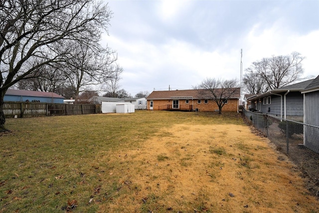 view of yard featuring an outbuilding, a fenced backyard, and a storage shed