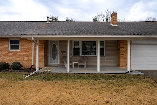 view of front of property featuring an attached garage, brick siding, roof with shingles, a chimney, and a front yard