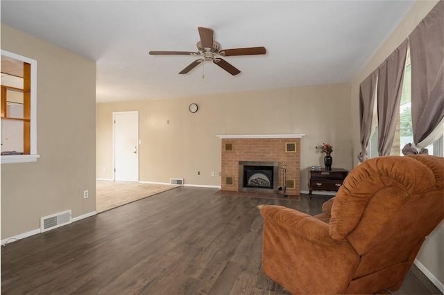 unfurnished living room with a brick fireplace, visible vents, baseboards, and wood finished floors