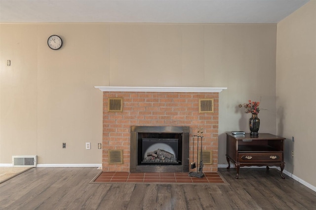 details featuring a brick fireplace, wood finished floors, and visible vents