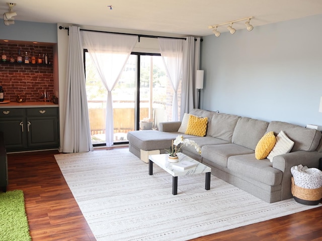 living room with brick wall, track lighting, and wood finished floors