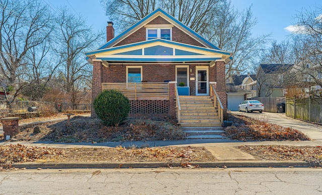 bungalow with stairway, fence, covered porch, a chimney, and brick siding