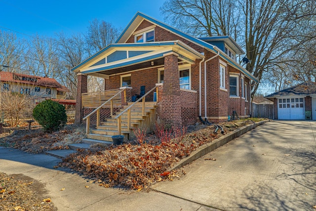 bungalow-style home featuring brick siding, stairway, covered porch, an outdoor structure, and a garage