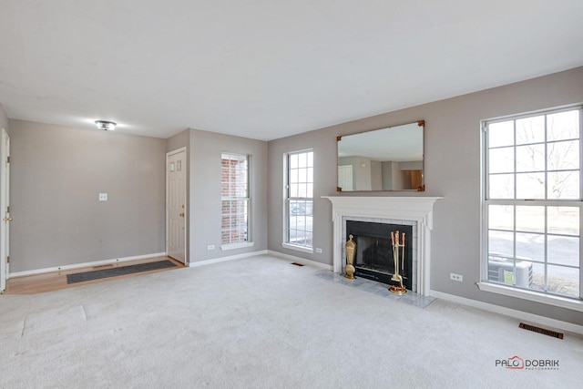 unfurnished living room with carpet, a fireplace with flush hearth, visible vents, and baseboards