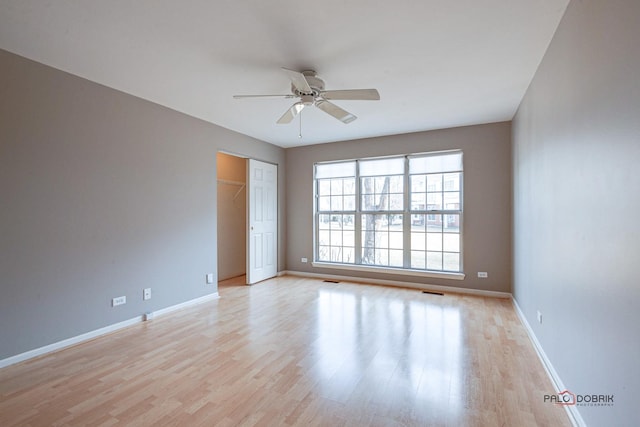 spare room featuring light wood-type flooring, baseboards, and a ceiling fan