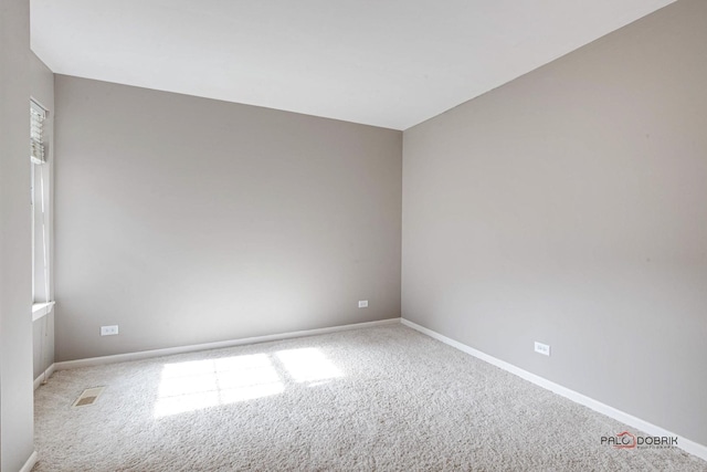 unfurnished room with carpet, visible vents, and baseboards