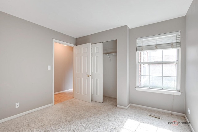 unfurnished bedroom with carpet floors, a closet, visible vents, and baseboards