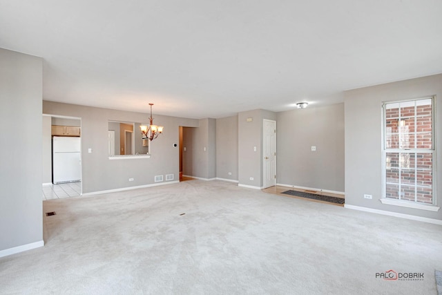 spare room with light colored carpet, a notable chandelier, visible vents, and baseboards