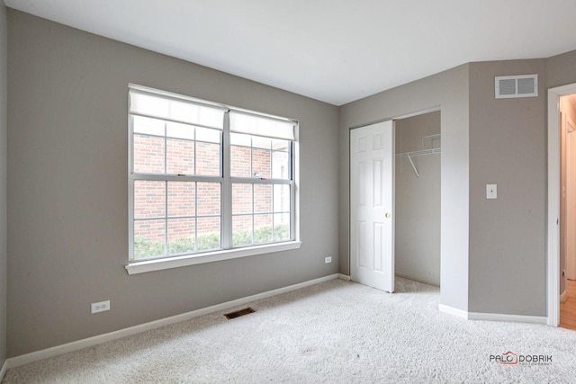 unfurnished bedroom with a closet, light colored carpet, visible vents, and baseboards