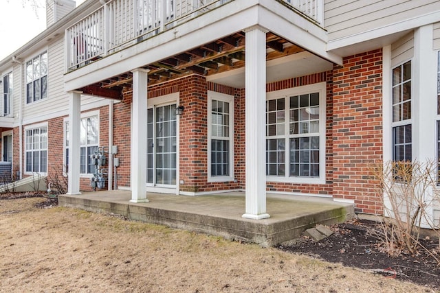 entrance to property featuring a porch and brick siding