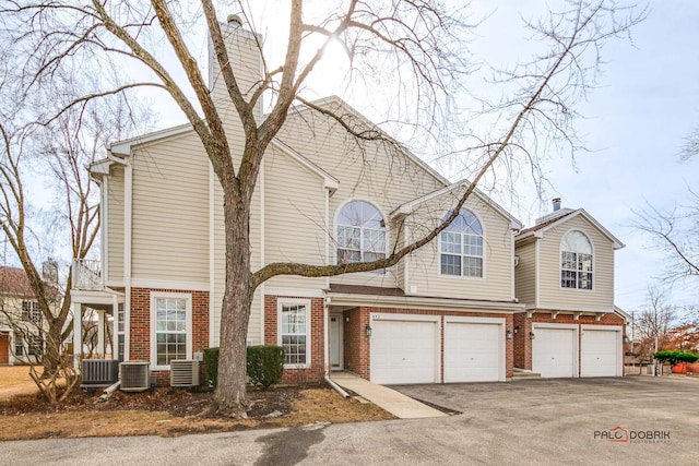 view of front of house with driveway, an attached garage, and brick siding