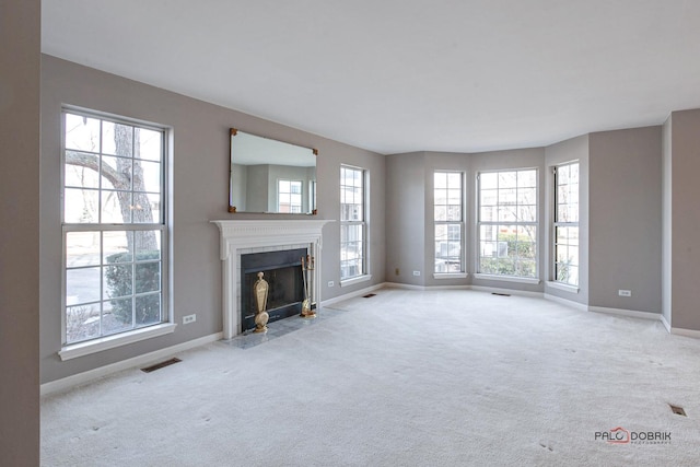 unfurnished living room with carpet floors, baseboards, visible vents, and a tile fireplace