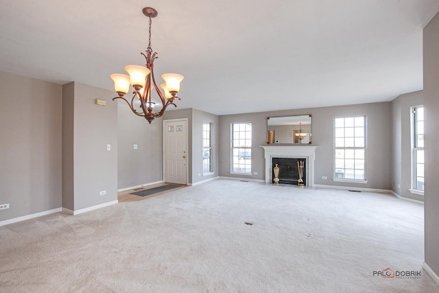 unfurnished living room with baseboards, carpet floors, a fireplace with flush hearth, and a notable chandelier