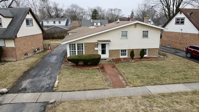 view of front of property with aphalt driveway, brick siding, and a front lawn