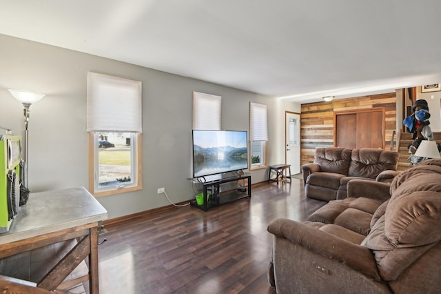 living room featuring dark wood-style floors, wood walls, and baseboards