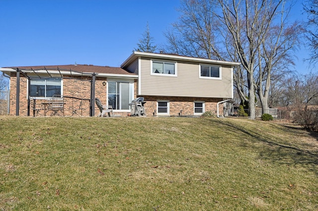 rear view of property with a yard, brick siding, and a pergola