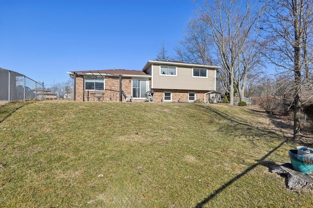 back of property with brick siding, a lawn, a pergola, and fence