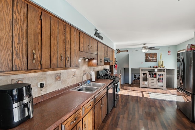 kitchen with tasteful backsplash, brown cabinets, dark wood-style floors, stainless steel appliances, and a sink