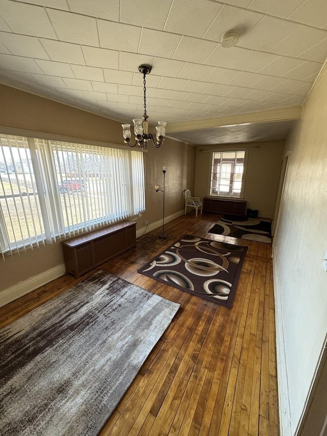 dining space with baseboards, hardwood / wood-style floors, radiator heating unit, and a notable chandelier