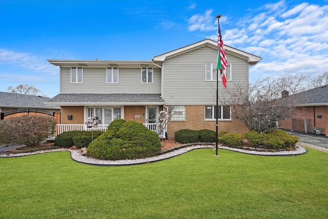 traditional-style home featuring a front yard, a porch, and brick siding