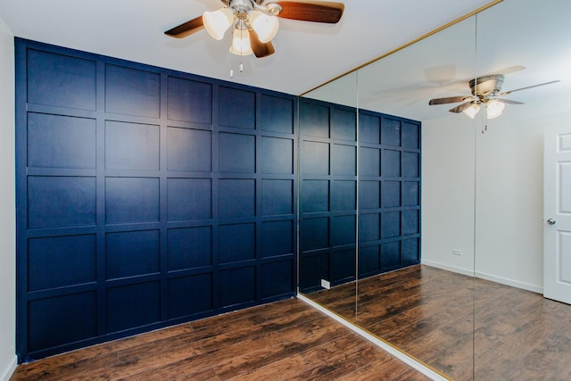 interior space featuring ceiling fan, a decorative wall, and wood finished floors