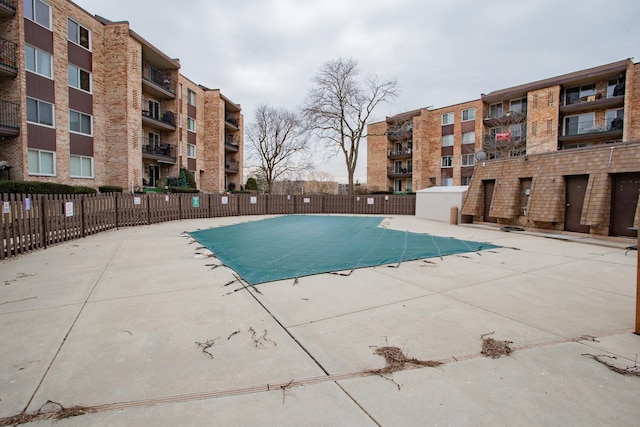 community pool with a patio area and fence