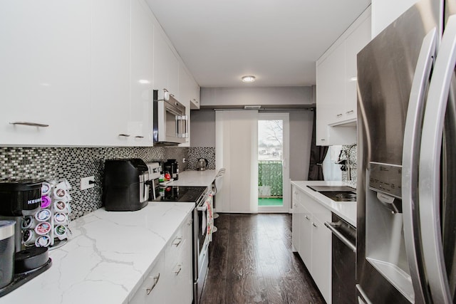 kitchen featuring white cabinets, dark wood finished floors, stainless steel appliances, and decorative backsplash