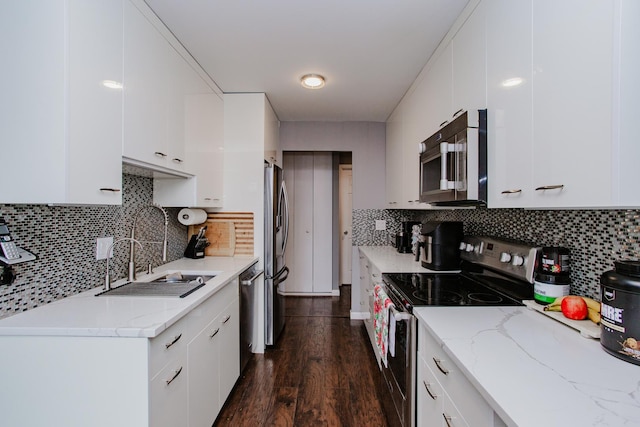 kitchen featuring stainless steel appliances, dark wood-style flooring, a sink, white cabinetry, and decorative backsplash