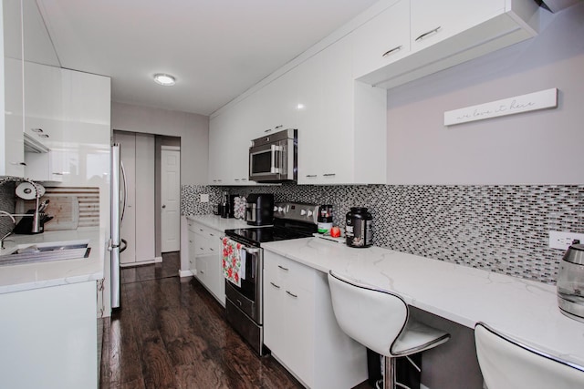 kitchen with stainless steel appliances, white cabinetry, and decorative backsplash